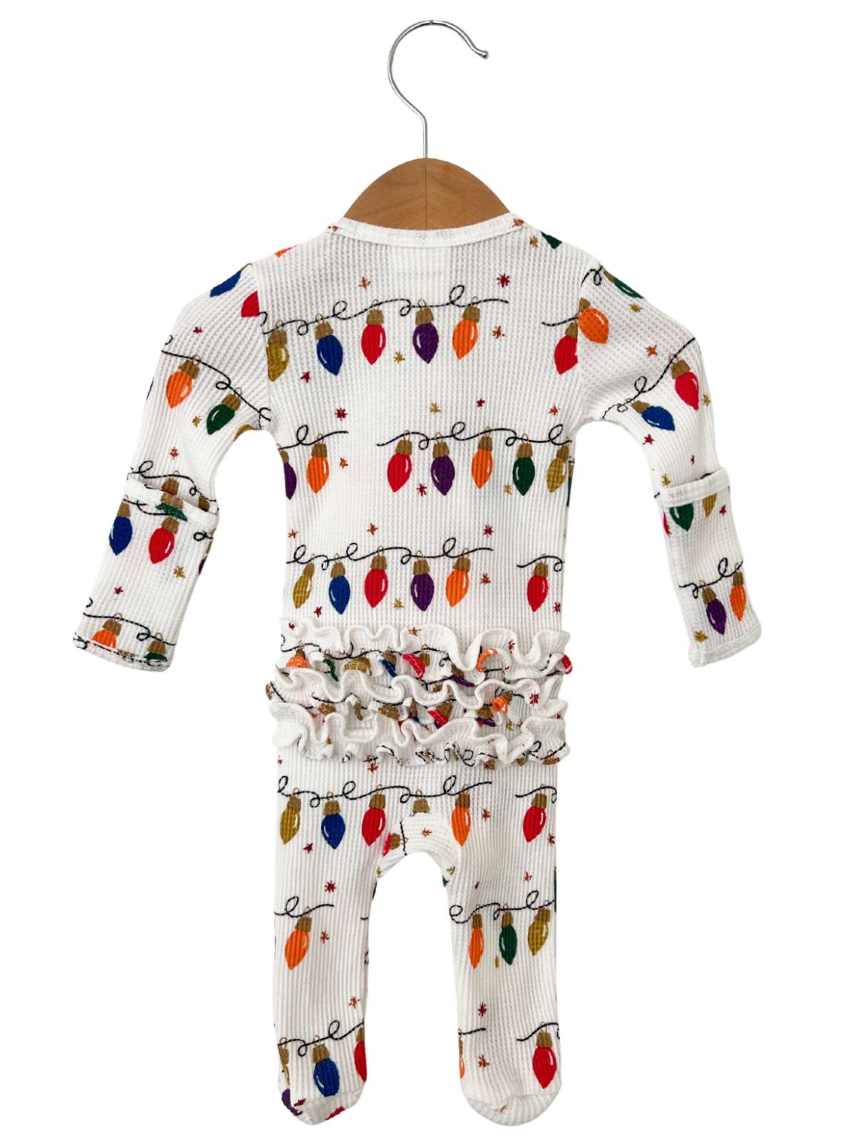 White baby onesie with colorful Christmas lights pattern, featuring ruffled waist and sleeves. Hanging on a wooden hanger.