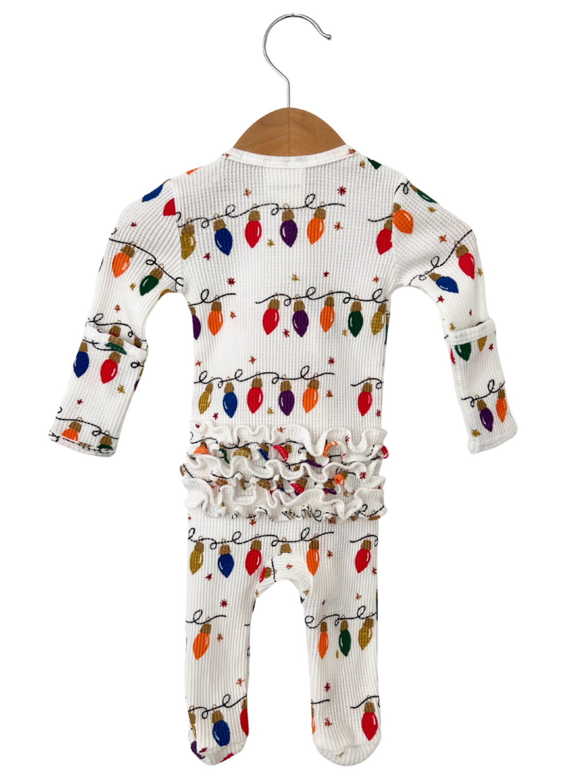White baby onesie with colorful Christmas lights pattern, featuring ruffled waist and sleeves. Hanging on a wooden hanger.