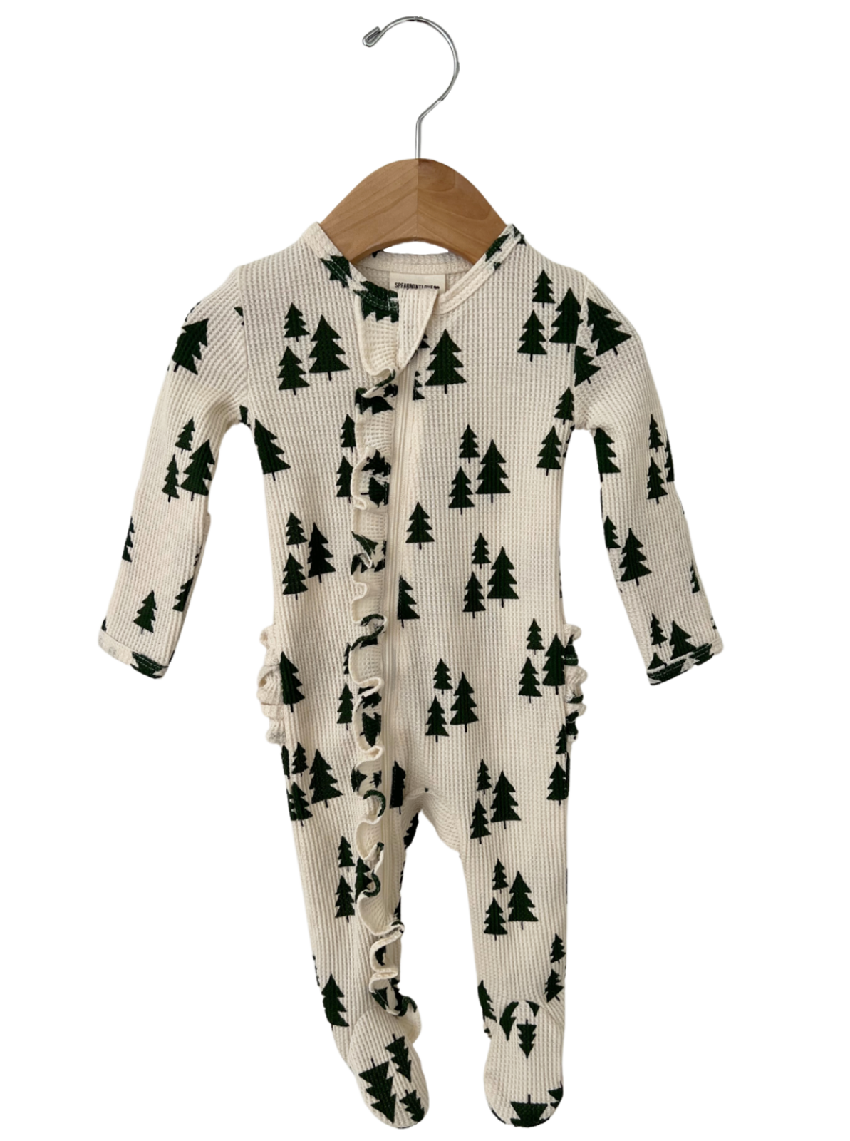Cream-colored baby onesie with green tree patterns, hanging on a wooden hanger.