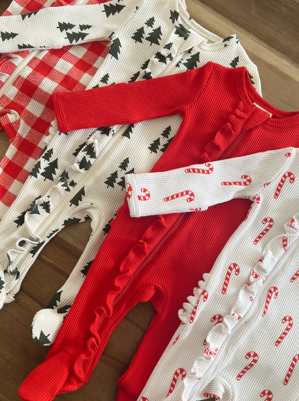 Set of festive children’s pajamas featuring Christmas patterns: candy canes, trees, and checkered designs.