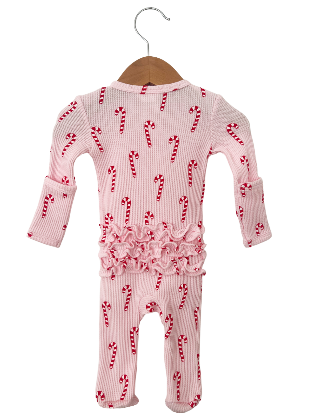 Pink baby onesie with candy cane pattern, featuring ruffled detailing at the waist, hanging on a wooden hanger.
