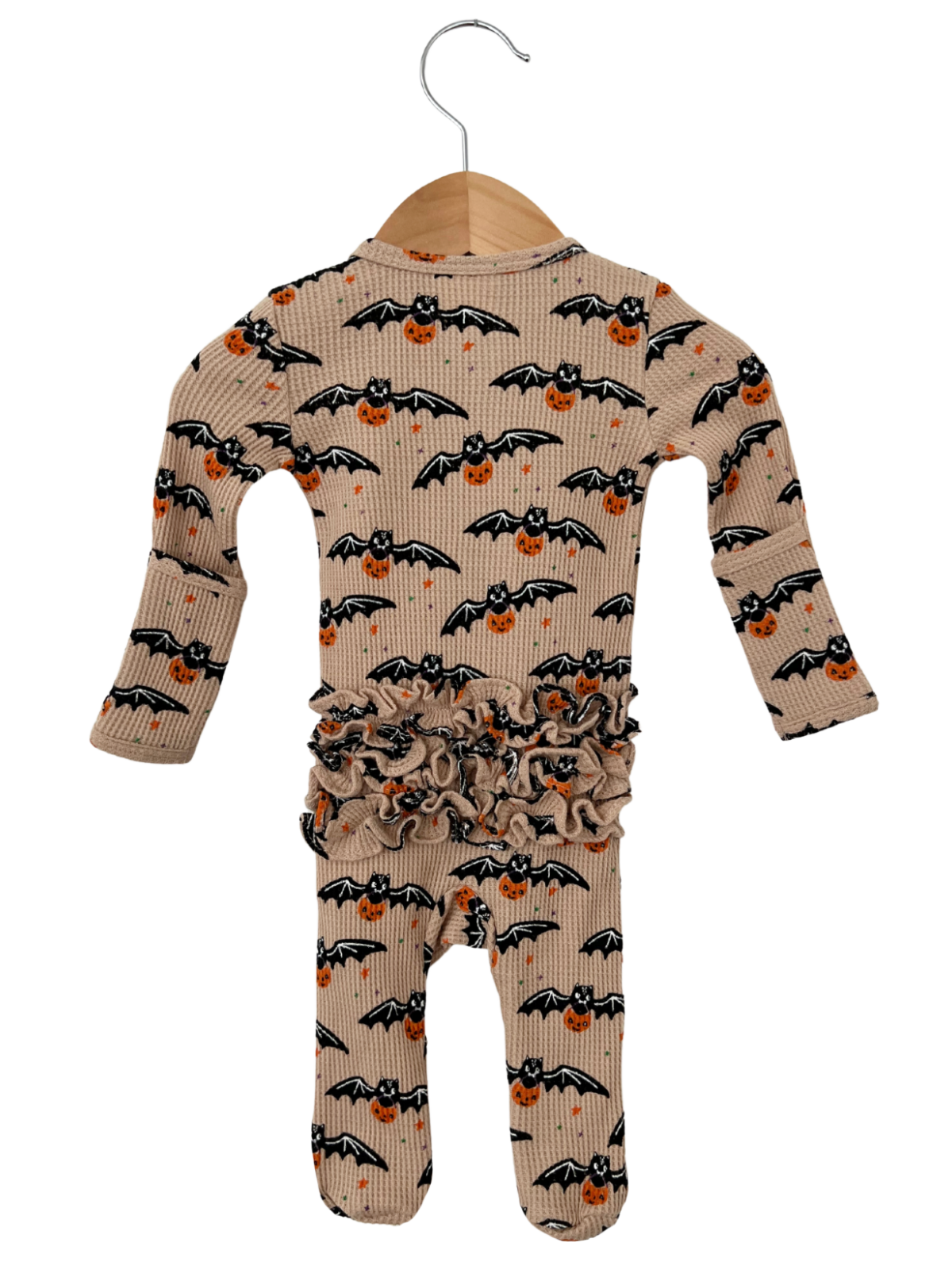 Beige baby romper with bat and pumpkin print, featuring ruffled waistband and hanging on a wooden hanger.
