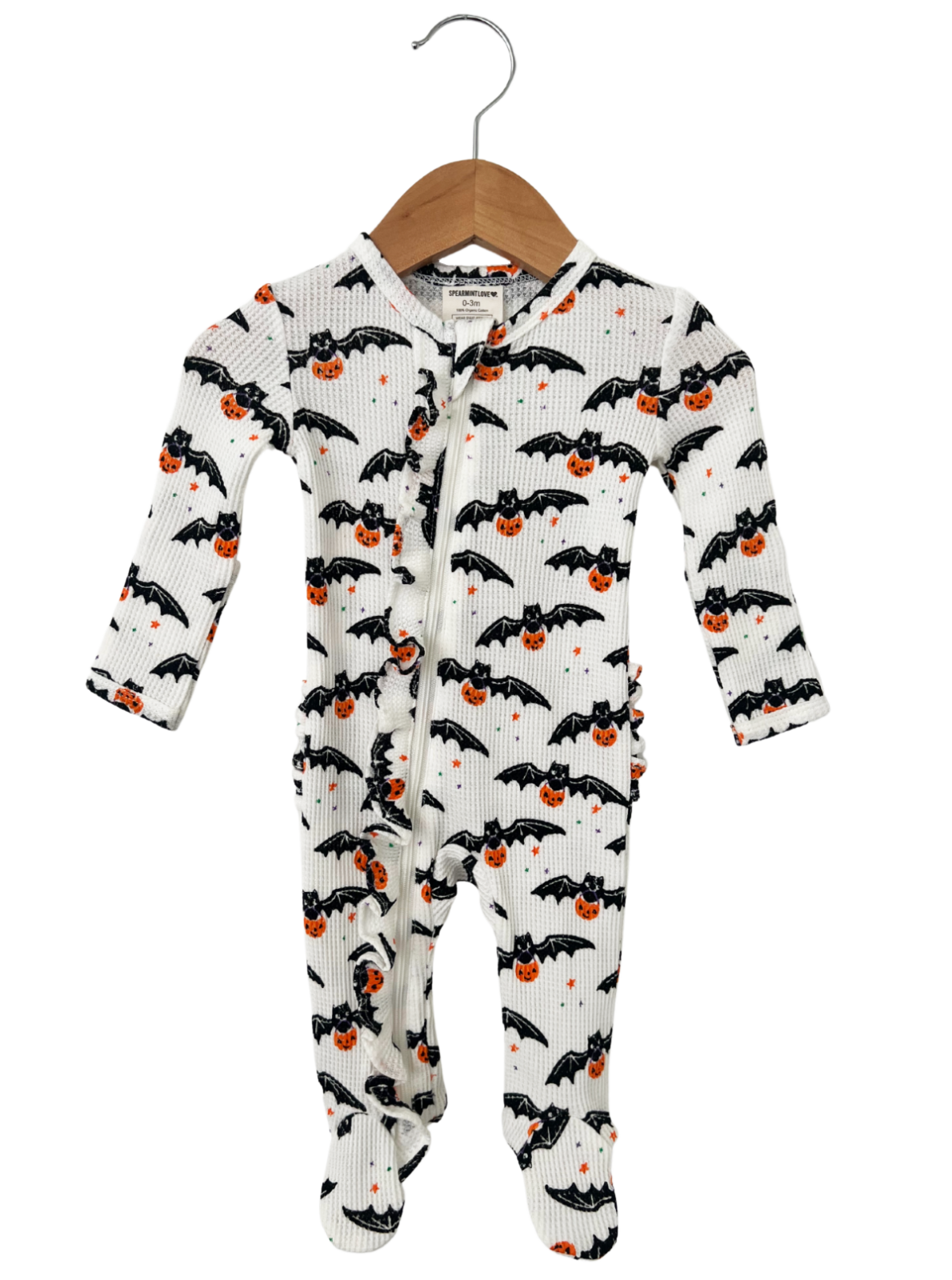 White bat-patterned onesie with orange pumpkins, hanging on a wooden hanger. Perfect for Halloween celebrations.
