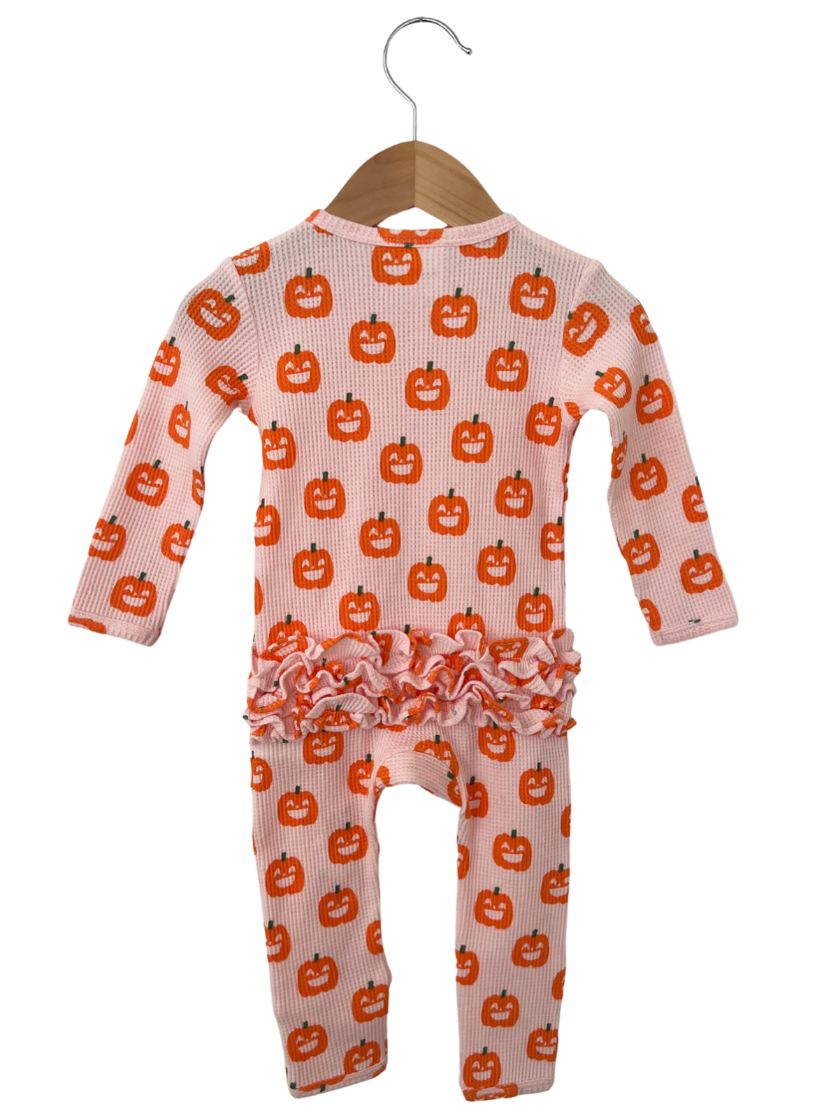 Pink baby outfit with pumpkin print and ruffled hem, hanging on a wooden hanger. Perfect for fall celebrations.
