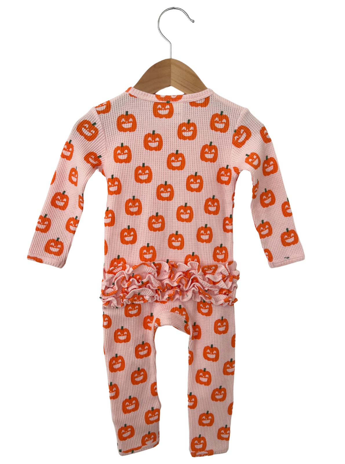 Pink baby outfit with pumpkin print and ruffled hem, hanging on a wooden hanger. Perfect for fall celebrations.