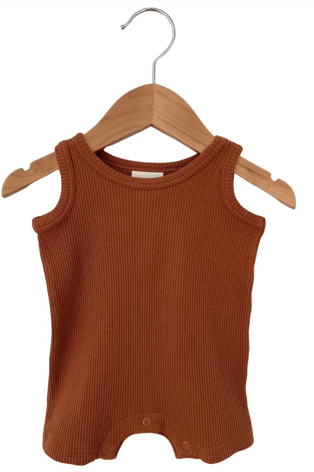 Rust-colored infant tank top with ribbed texture hanging on a wooden hanger.