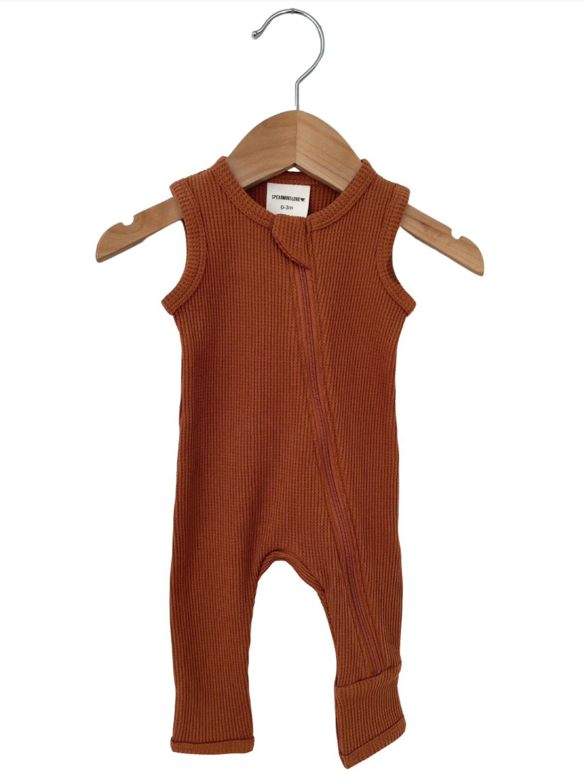 Rust orange ribbed baby romper hanging on a wooden hanger against a white background.