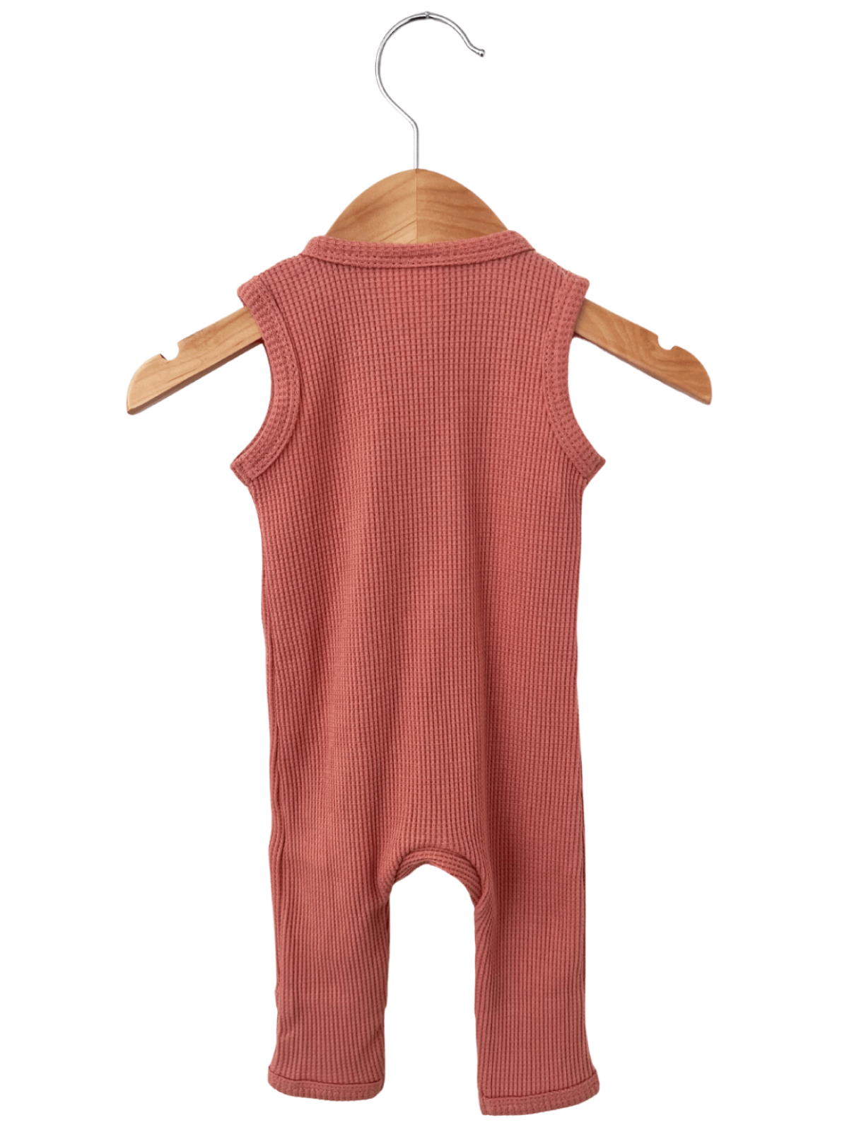 Light pink sleeveless baby romper hanging on a wooden hanger against a white background.