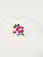 White knitted sweater with a pink rose design, perfect for toddlers or infants.