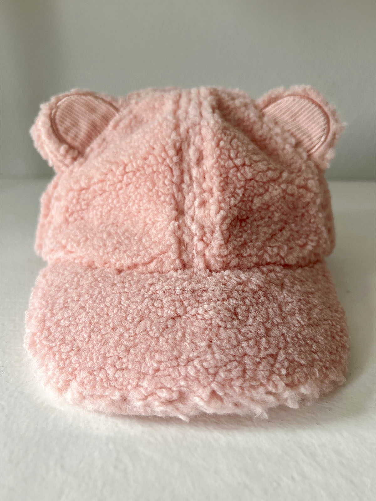Pink teddy bear cap with ears, soft texture, perfect for children.