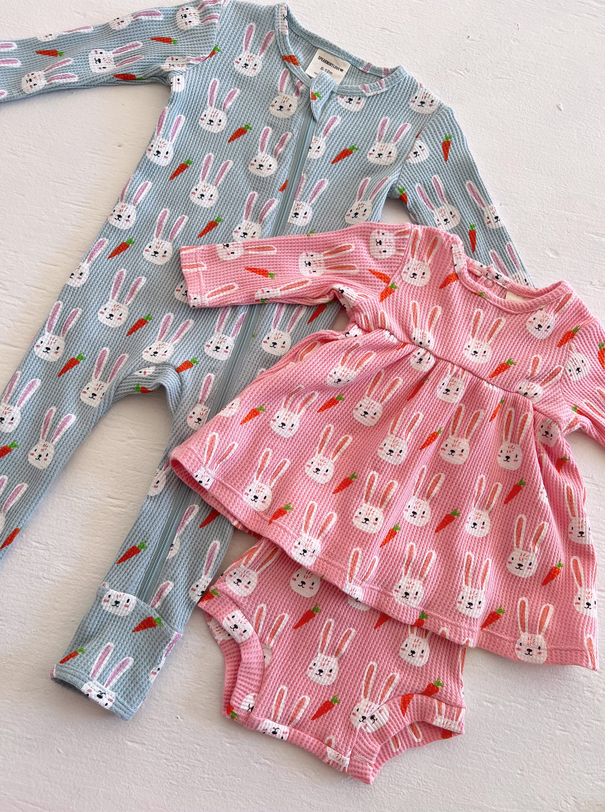 Three adorable baby outfits featuring bunny and carrot patterns in shades of blue and pink.