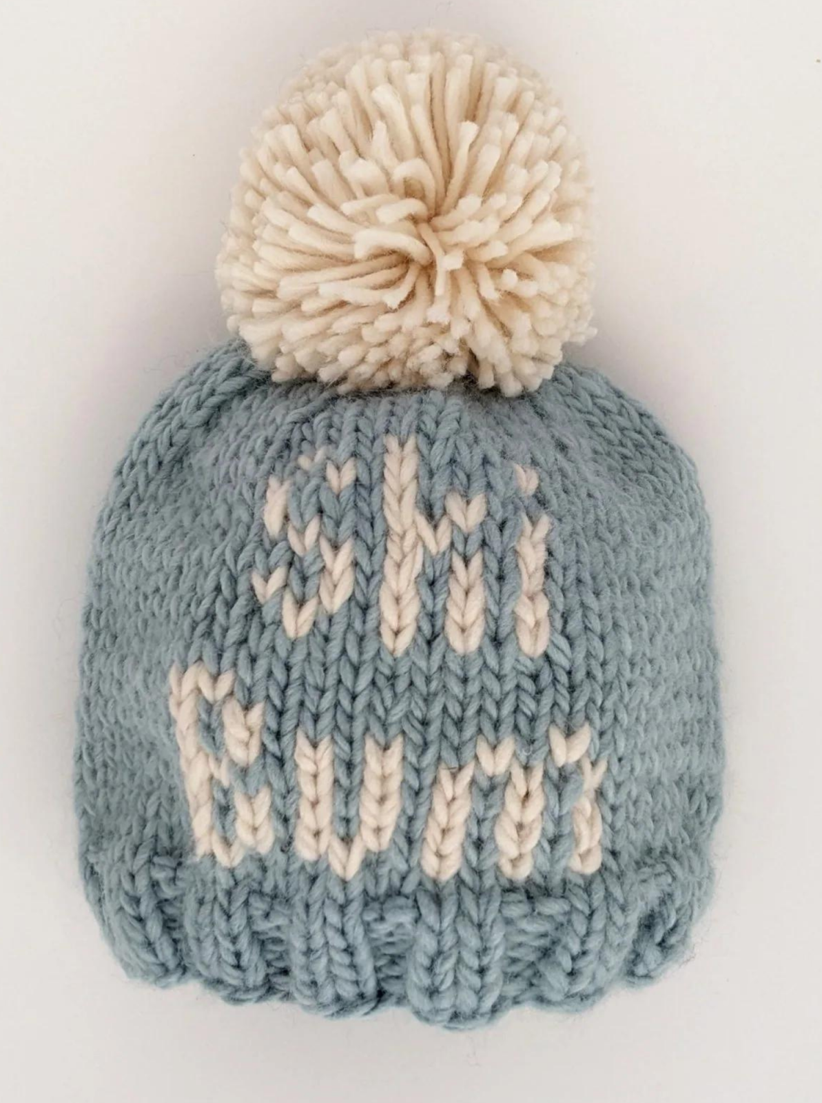 Light blue knitted beanie with a white pom-pom and the text "ski bums" on the front.