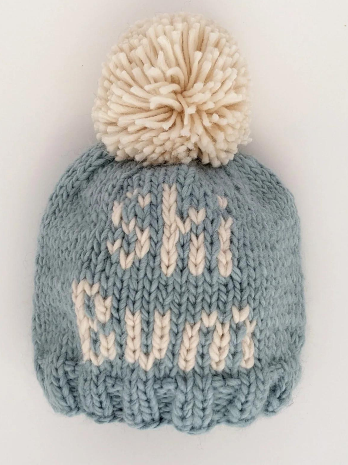 Light blue knitted beanie with a white pom-pom and the text "ski bums" on the front.