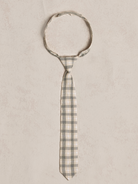 Gray and cream checkered tie laid flat on a light textured background.