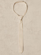 Beige striped tie displayed on a textured background.