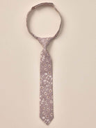 Floral patterned tie hanging against a neutral background, showcasing delicate leaves and blossoms.