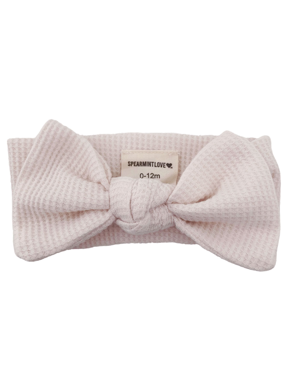 Pink textured baby headband with a large bow and a tag labeled "SPEARMINTLOVE 0-12m."