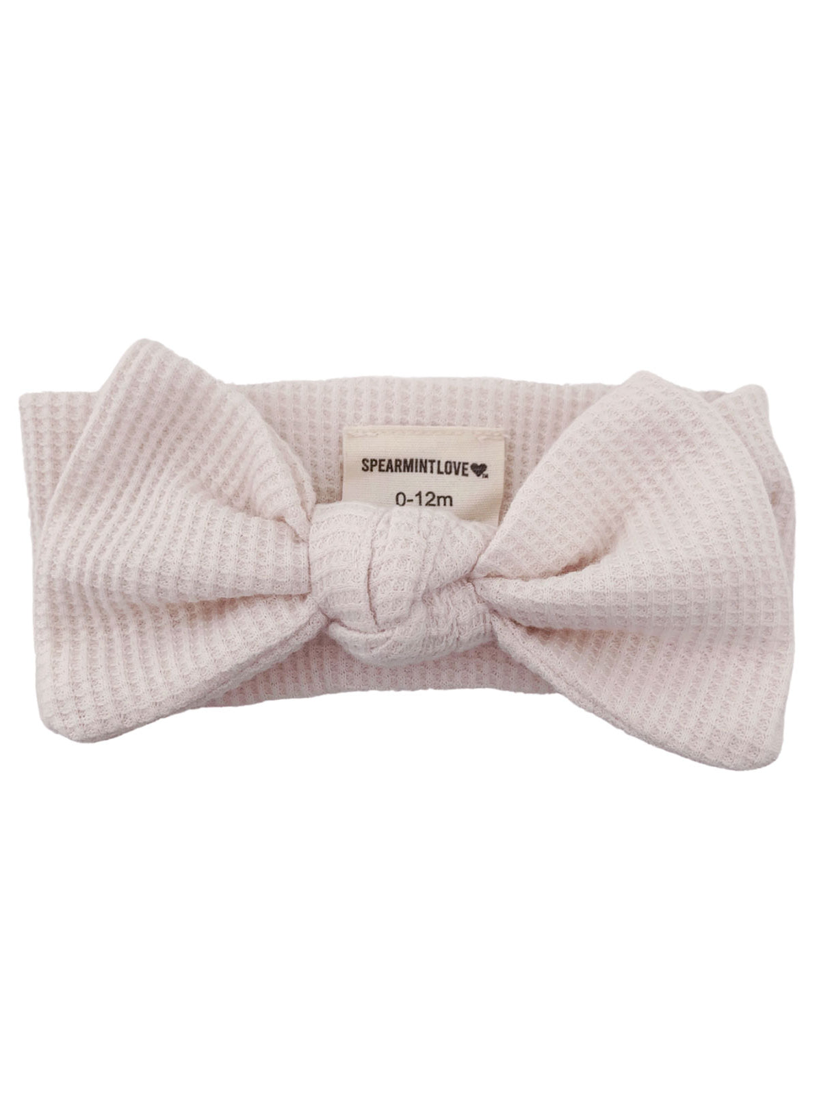 Pink textured baby headband with a large bow and a tag labeled "SPEARMINTLOVE 0-12m."