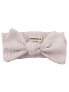Pink textured baby headband with a large bow and a tag labeled "SPEARMINTLOVE 0-12m."