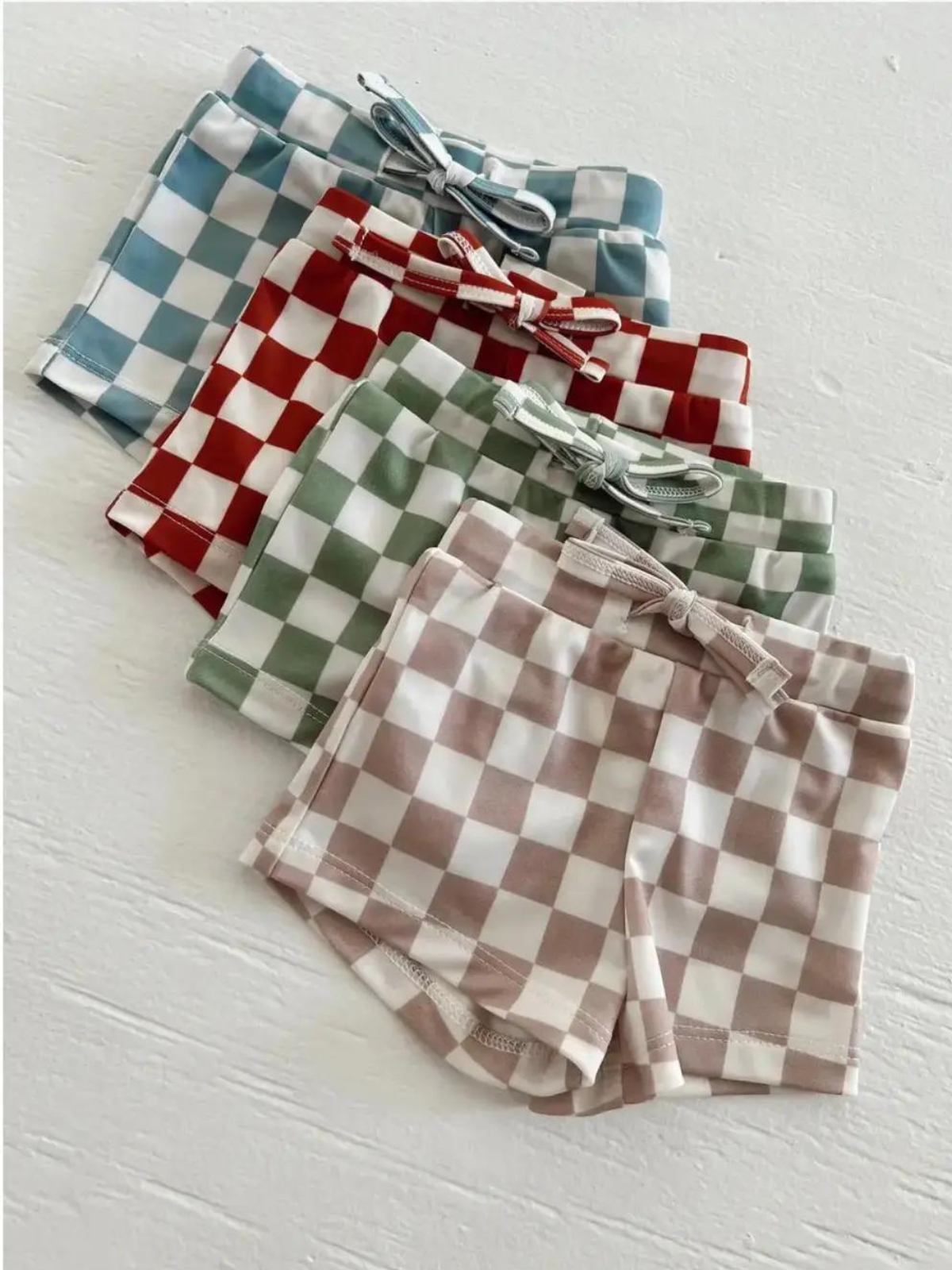 Colorful checkered shorts in blue, red, green, and brown arranged neatly on a white background.