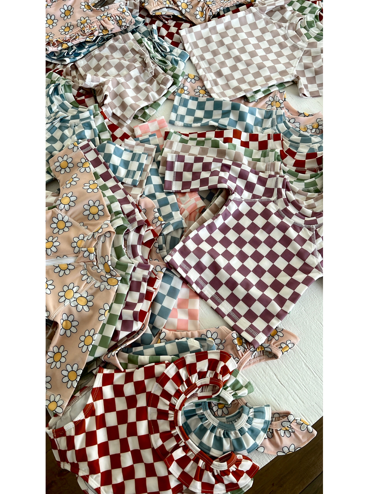Colorful children's clothing featuring floral and checkered patterns, including tops and blouses stacked together.