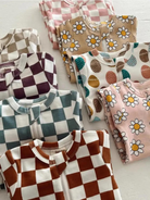 Colorful children's pajamas with various patterns, including checks, daisies, and Easter eggs, neatly folded.