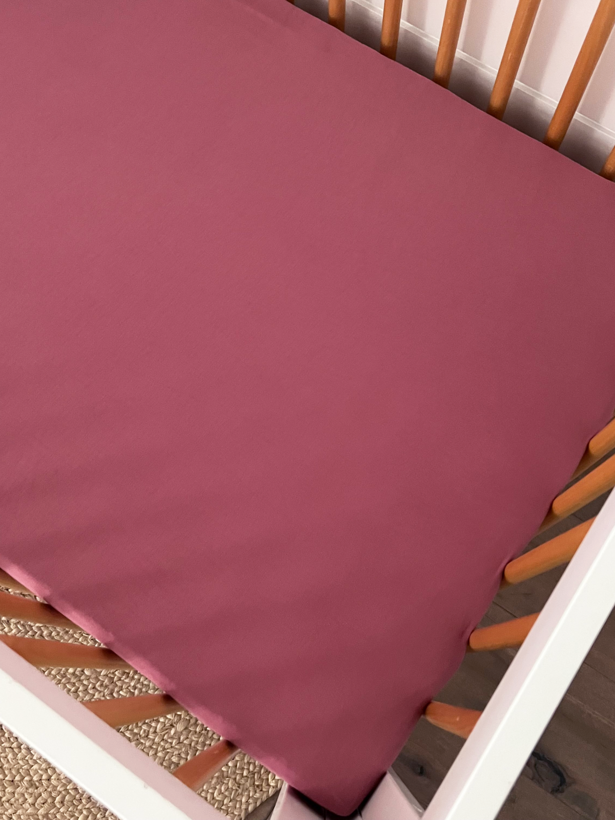 Crib with a pink fitted sheet, showcasing a cozy sleeping space for infants.
