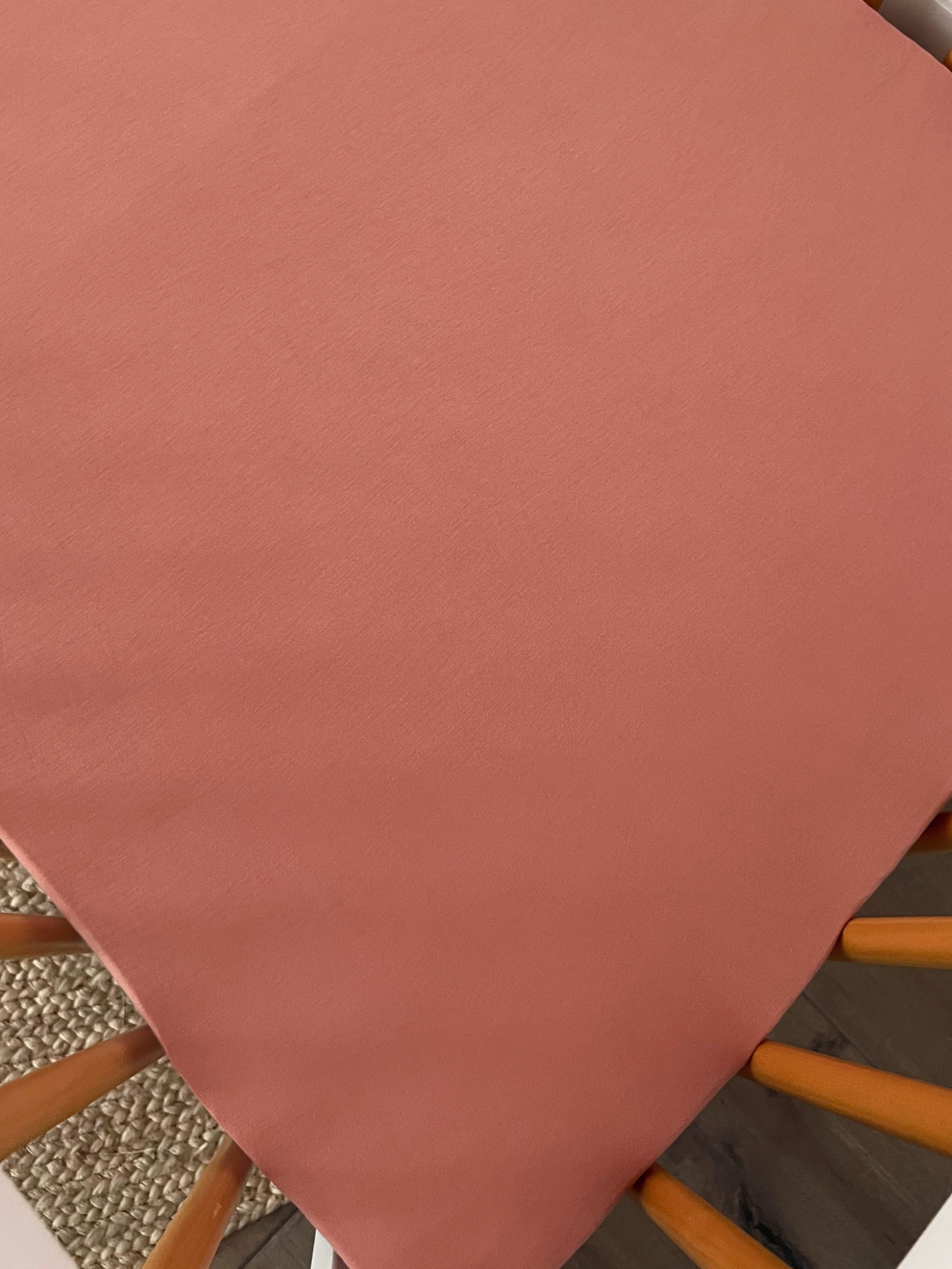 Solid coral-colored fabric draped over a chair, showcasing a soft texture and modern decor.