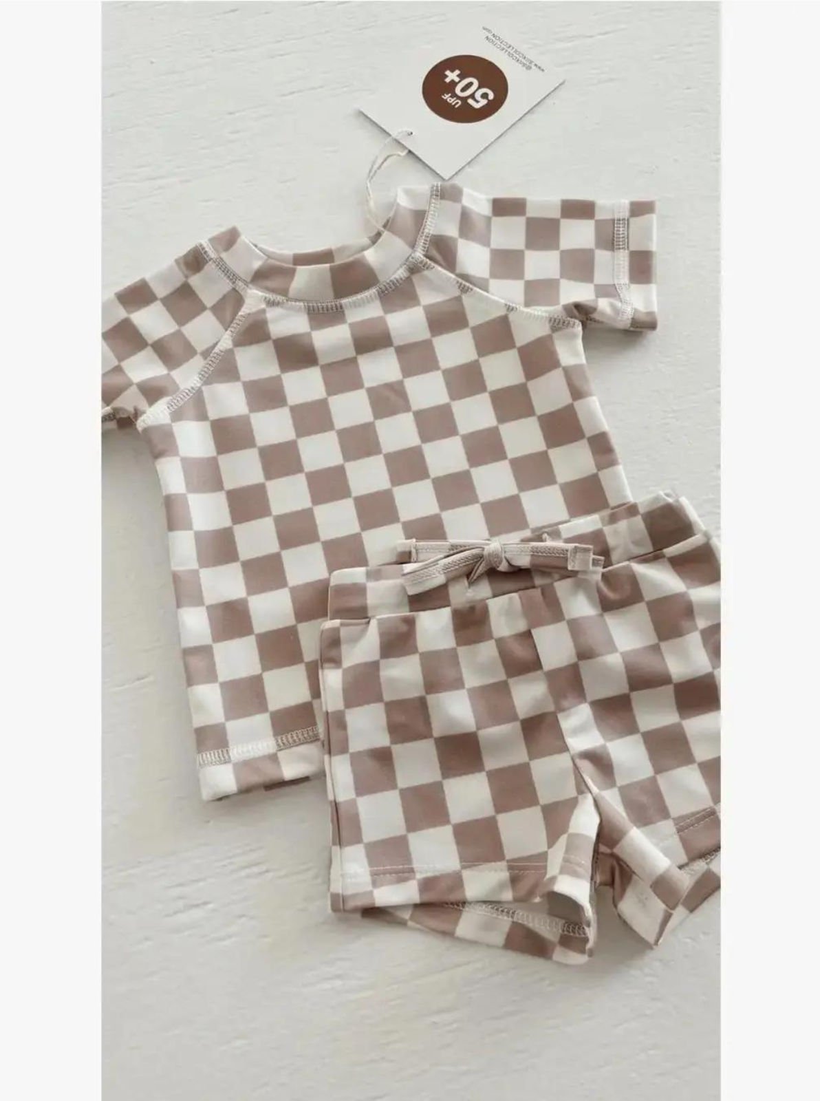 Brown and white checkered toddler swimsuit set with a short-sleeve top and matching shorts.