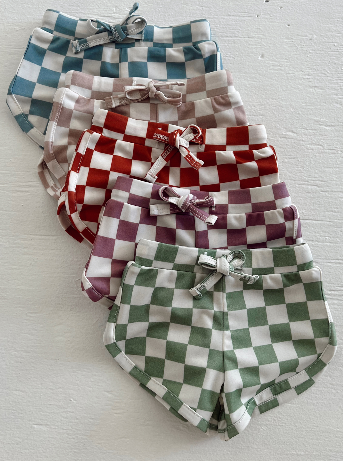 Colorful checkered shorts stacked in rows, featuring blue, pink, red, purple, and green patterns.