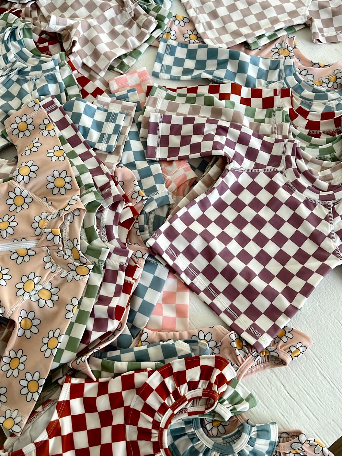 Colorful mix of patterned children's shirts in checkered and floral designs arranged on a light background.