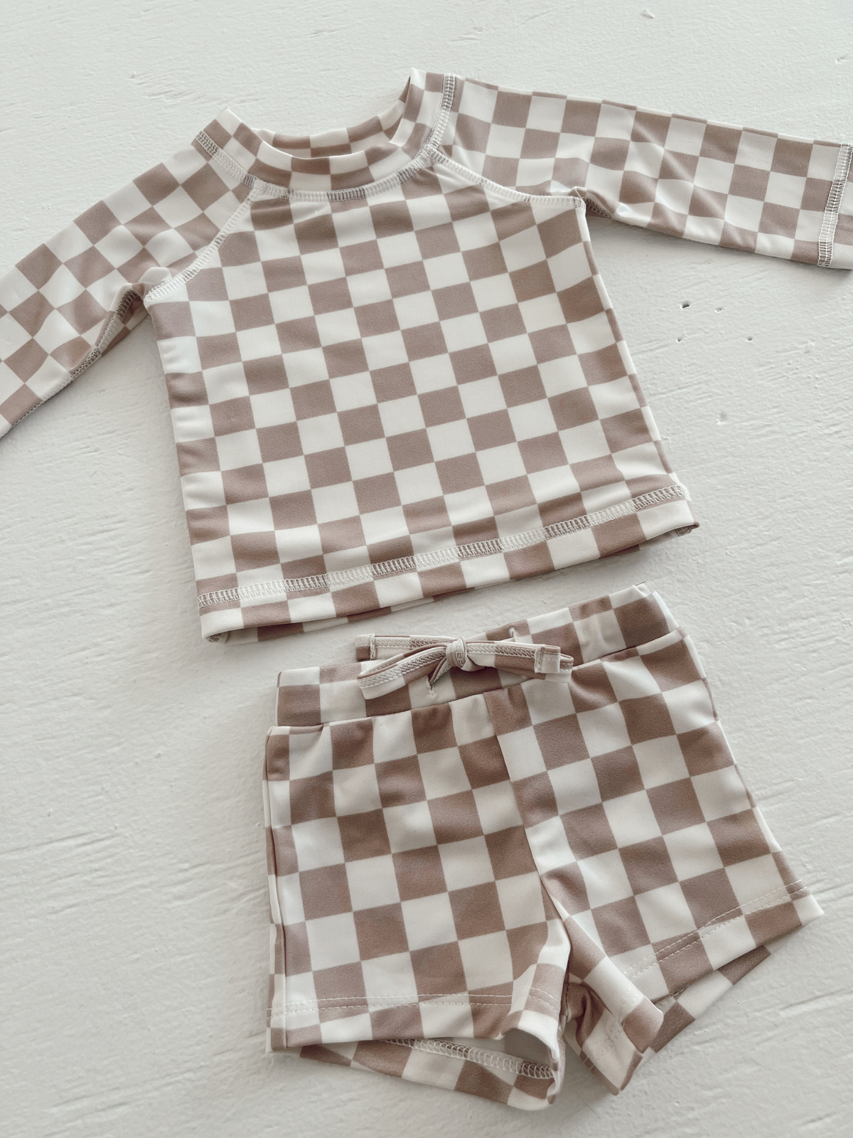 Tan and white checked swim set for kids, featuring a long-sleeve top and matching shorts.