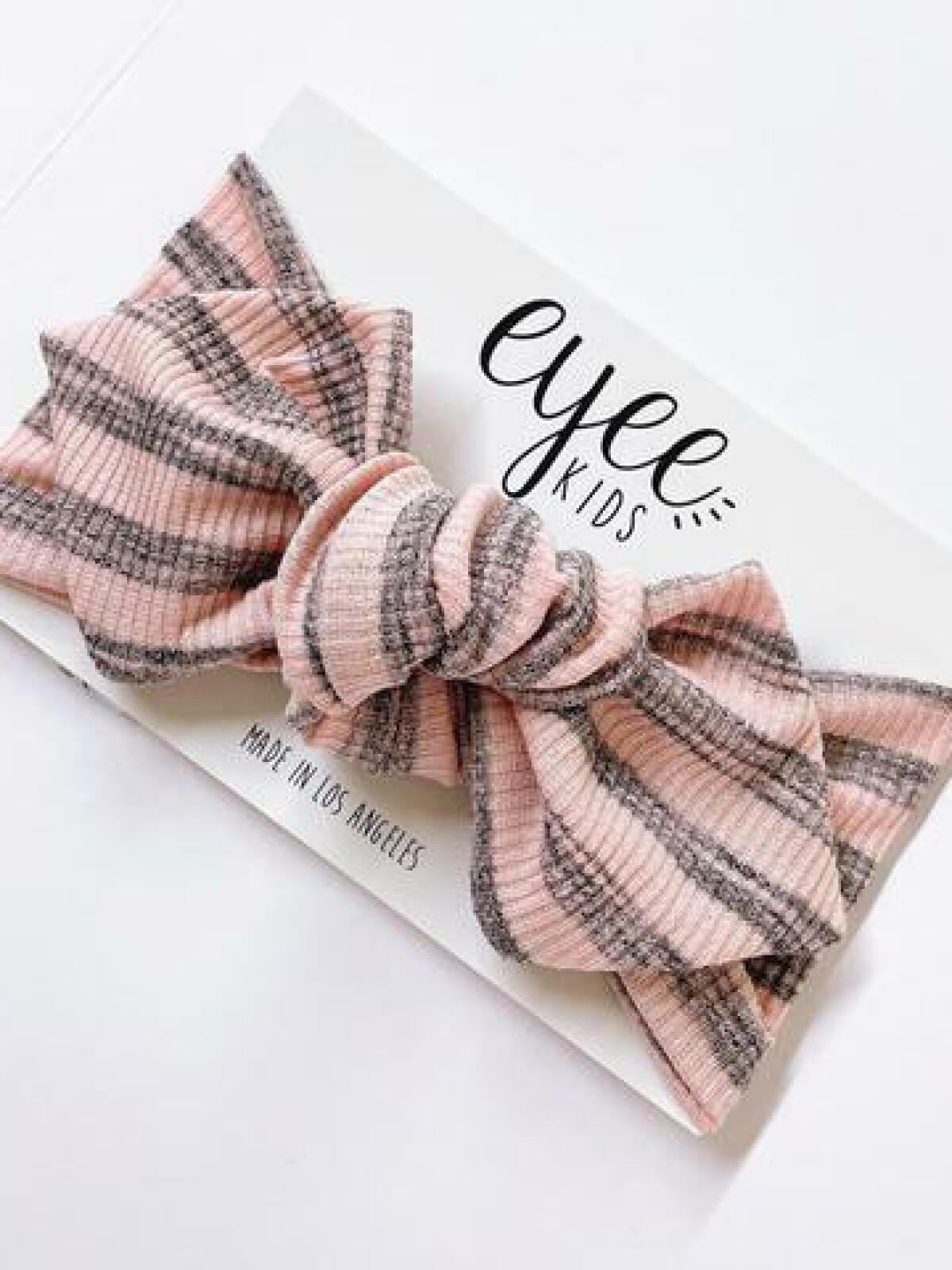 Pink and gray striped headband laid on a card that reads "eyee KIDS, Made in Los Angeles."