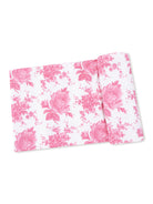 Pink floral fabric with roses and small blossoms on a white background, neatly rolled. Perfect for sewing projects.