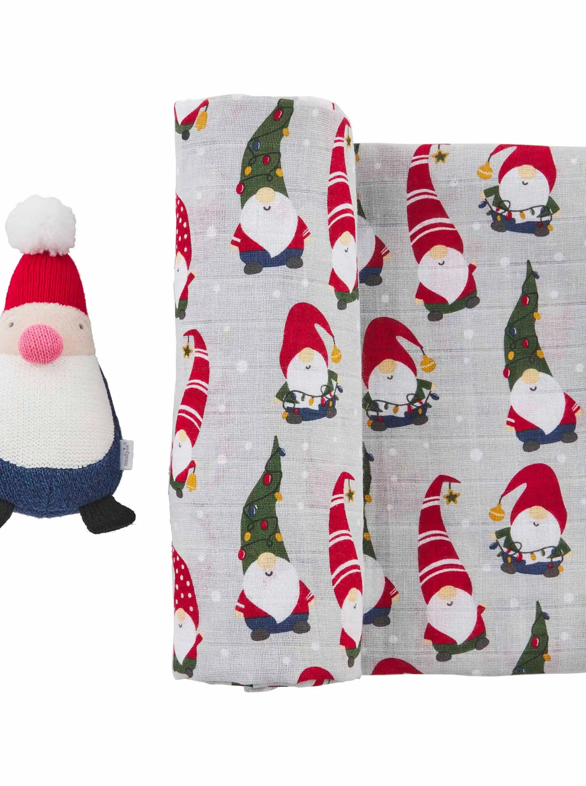 Plush gnome toy beside a fabric featuring festive gnome patterns on a light gray background.