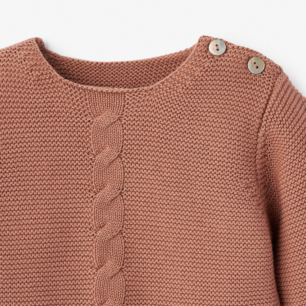 Brown knit sweater with a cable pattern and decorative buttons at the shoulder.