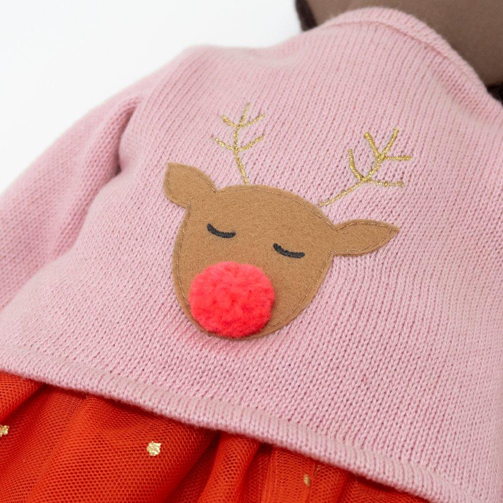 Pink sweater with a reindeer face, featuring closed eyes and a red pom-pom nose, paired with an orange skirt.