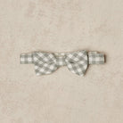 Gray and white checkered bow tie on a beige textured background.