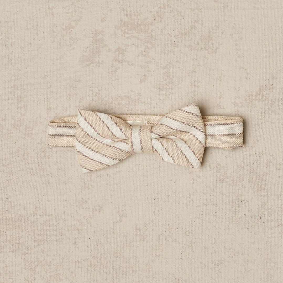 Beige and cream striped bow tie on a beige background. Classic accessory for formal occasions.