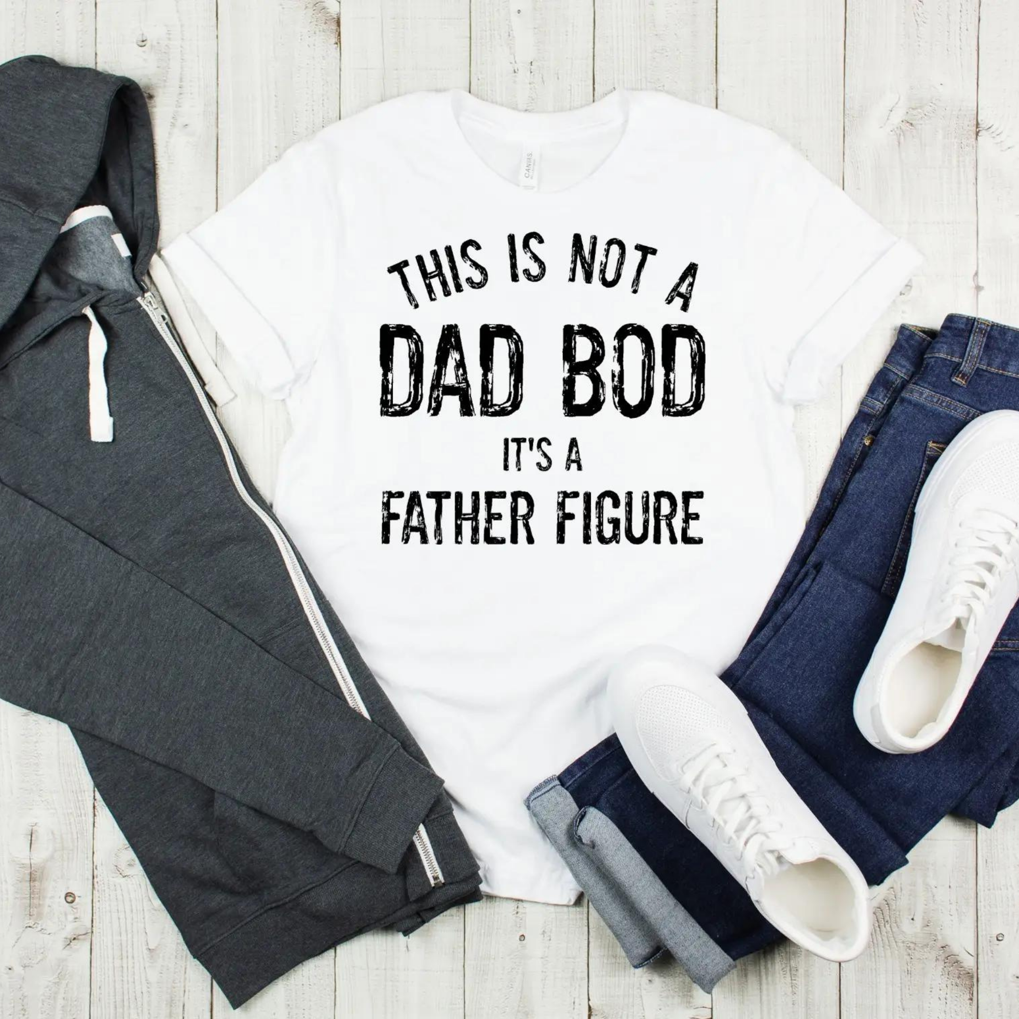 White t-shirt with "This is not a Dad Bod, it's a Father Figure" text, styled with hoodie, jeans, and sneakers.