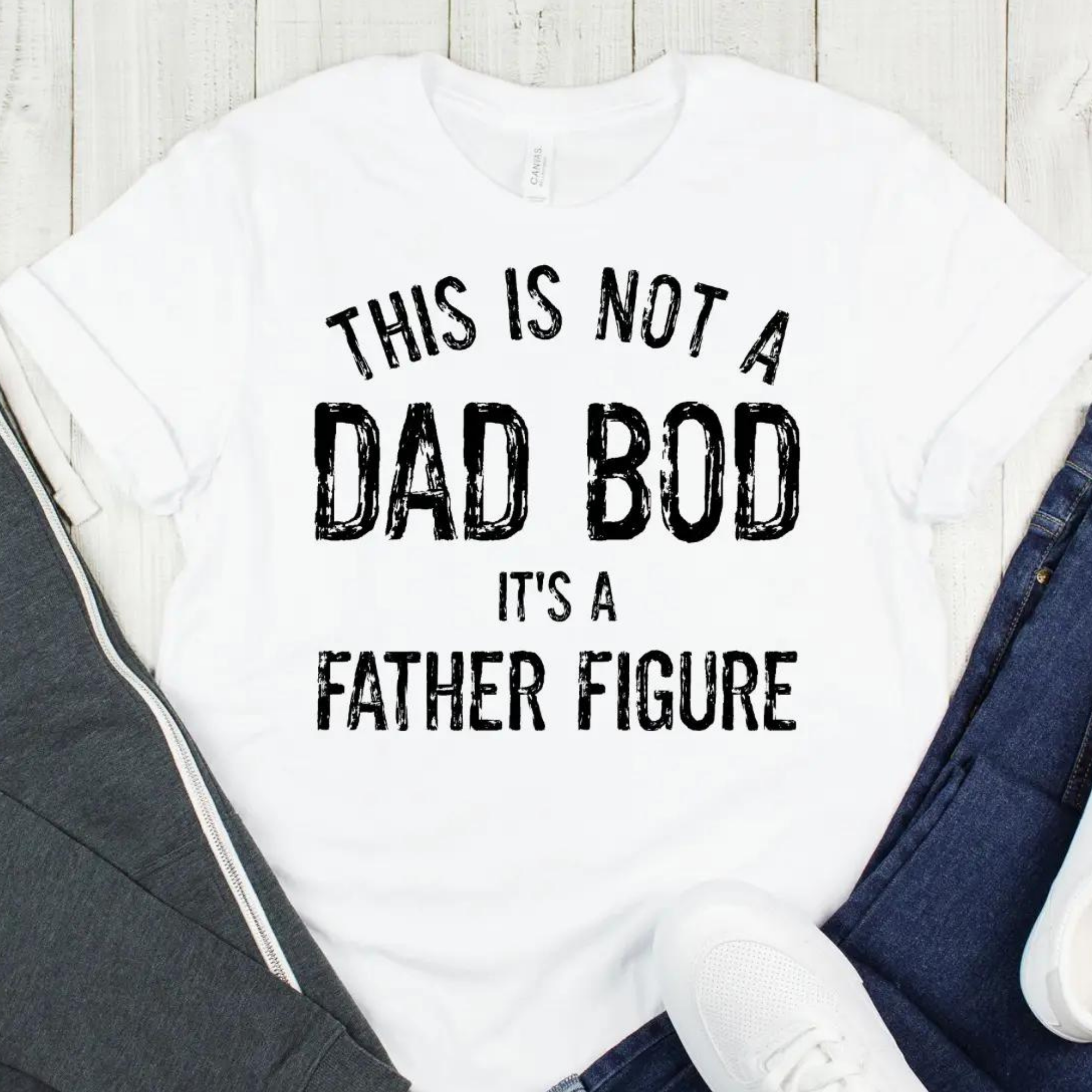 White T-shirt with text: "This is not a Dad Bod, it's a Father Figure," styled with casual clothing.