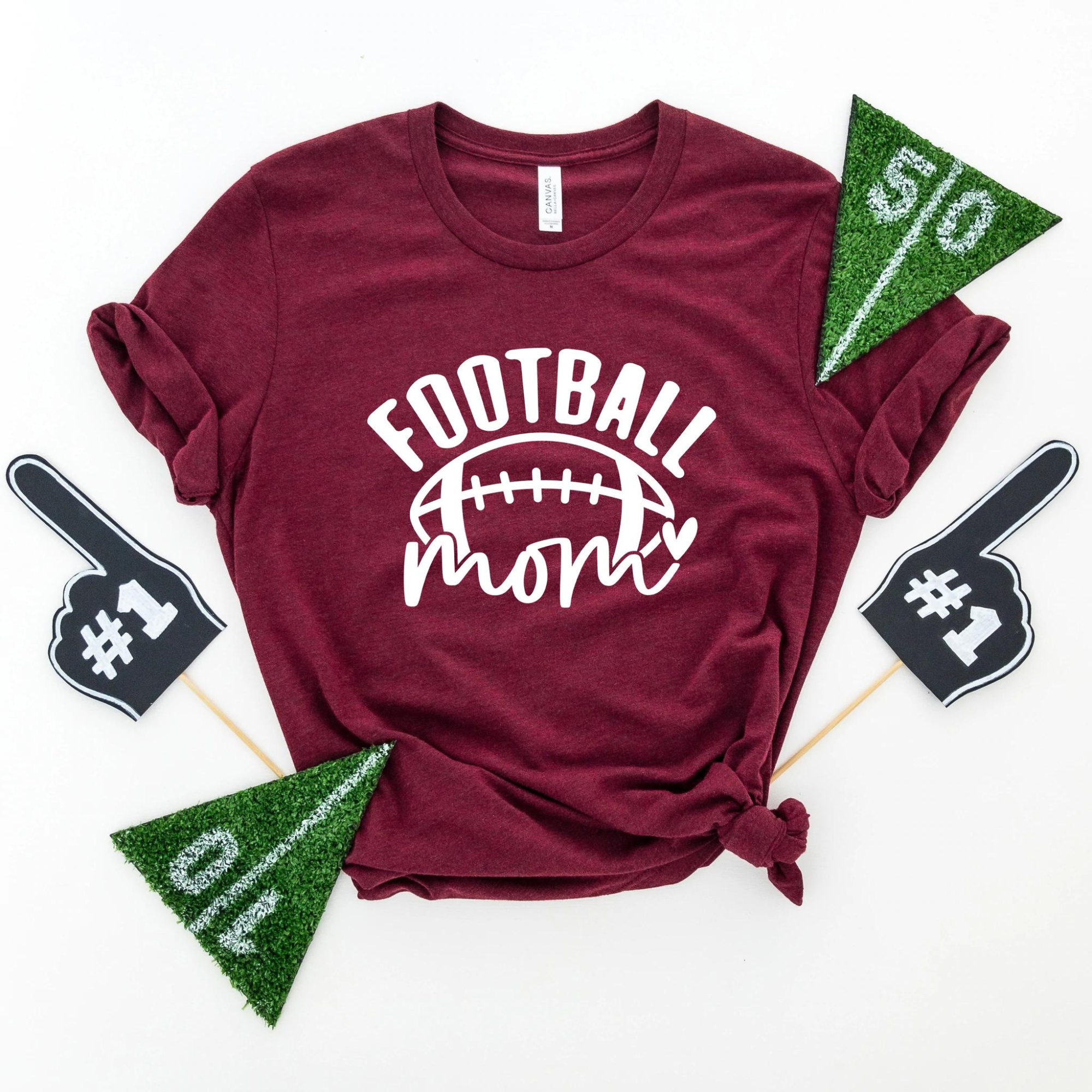 Maroon t-shirt with "FOOTBALL mom" text, surrounded by foam fingers and felt pennants for game day.