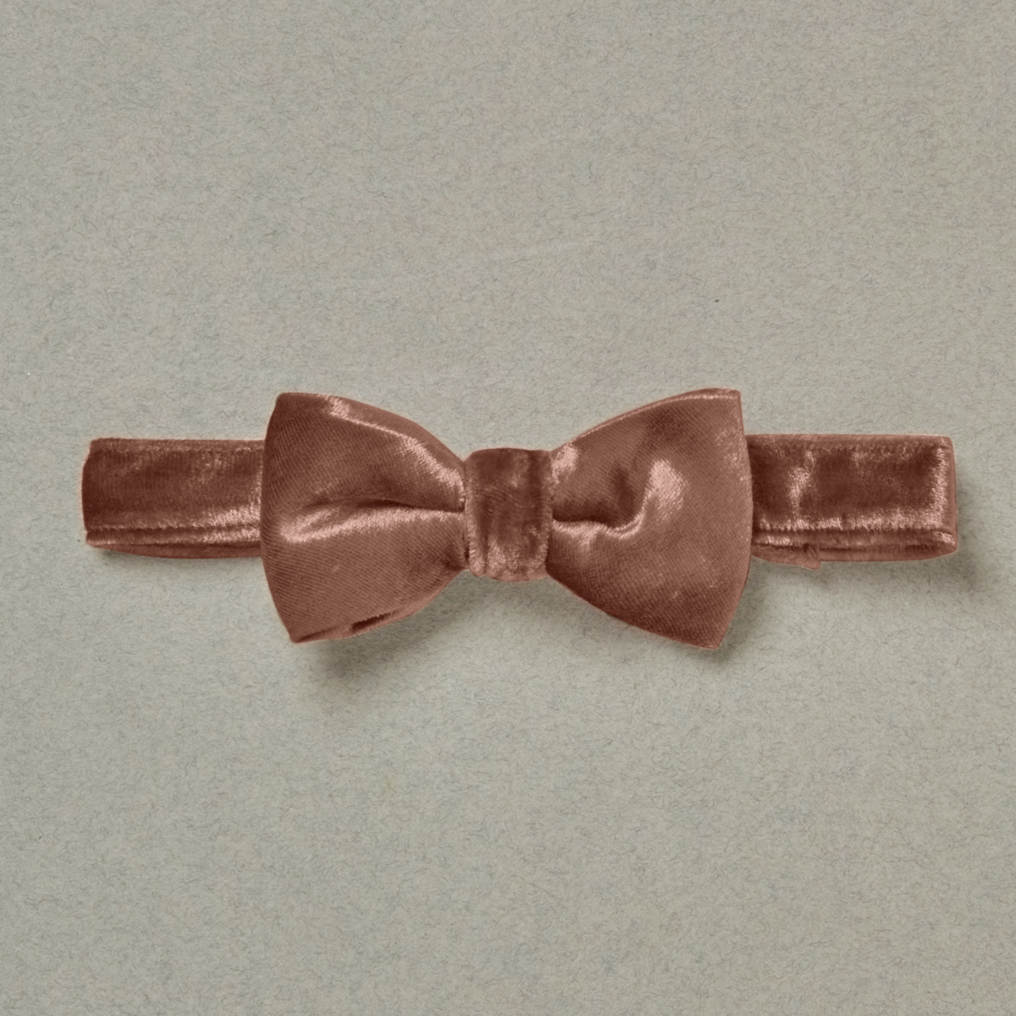 Rose velvet bow tie on a light gray background, showcasing its soft texture and elegant design.
