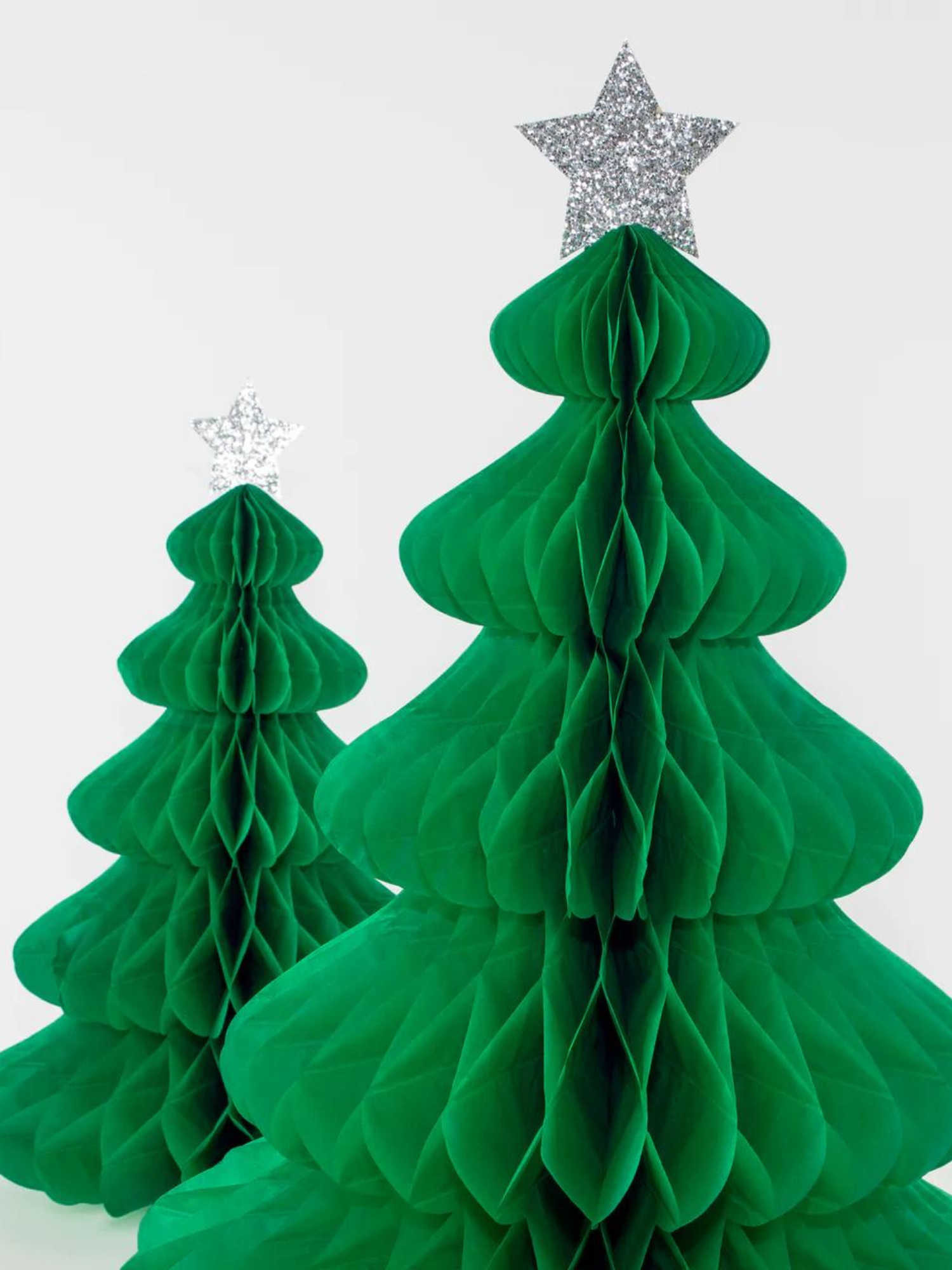 Green paper honeycomb Christmas trees with silver star toppers on a white background.