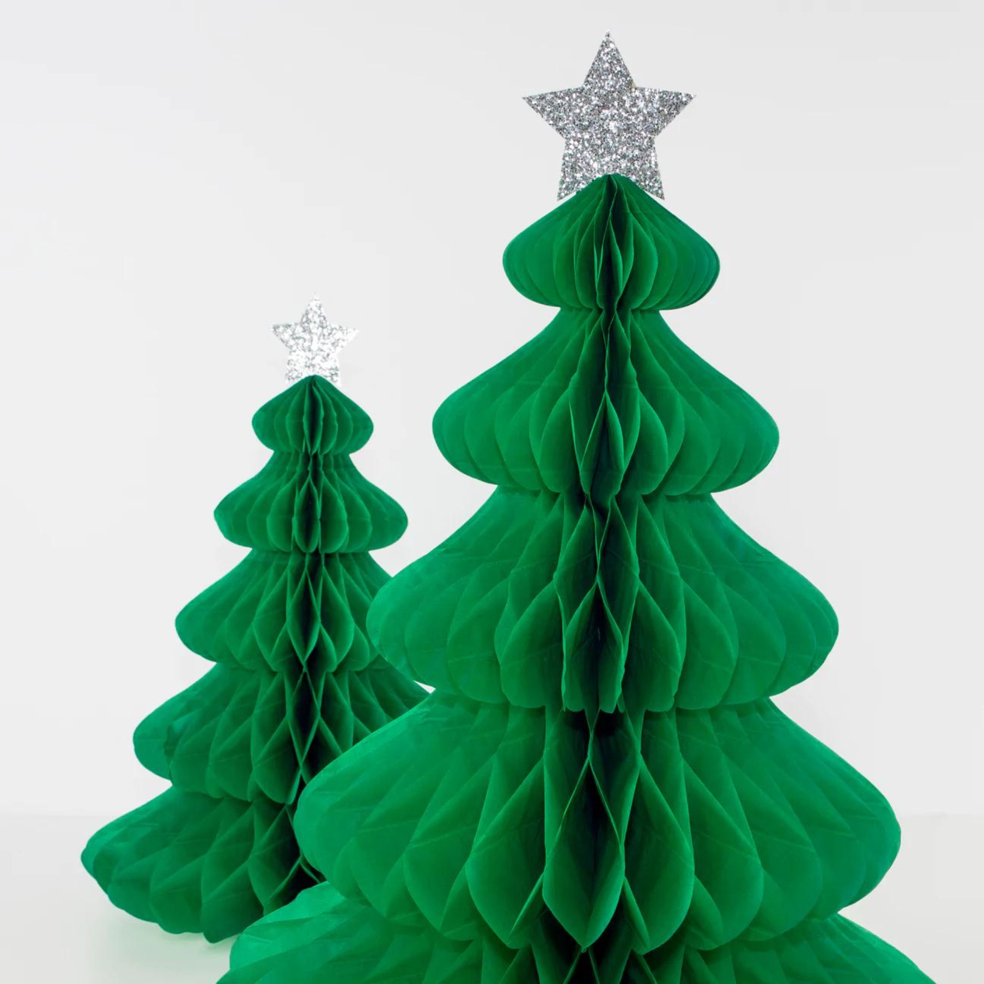 Green paper honeycomb Christmas trees with silver star toppers on a white background.