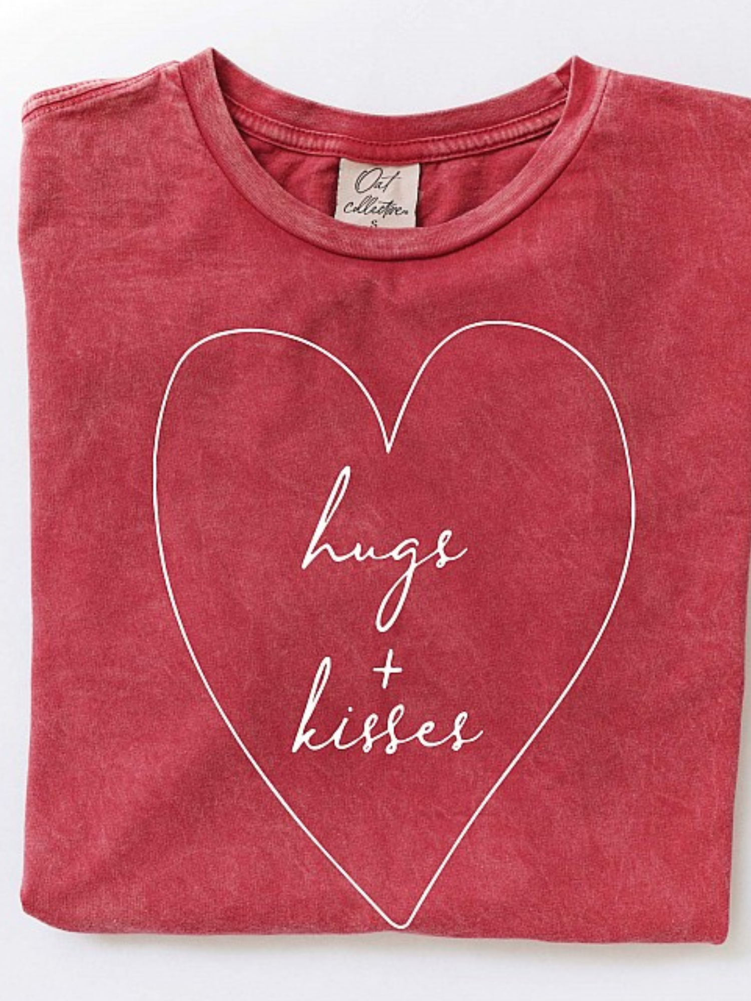 Red shirt folded with "hugs + kisses" in a heart design on the front.