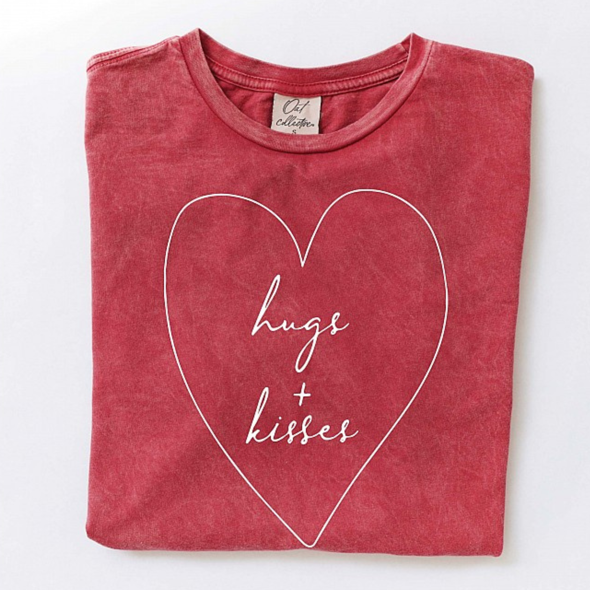 Red shirt folded with "hugs + kisses" in a heart design on the front.