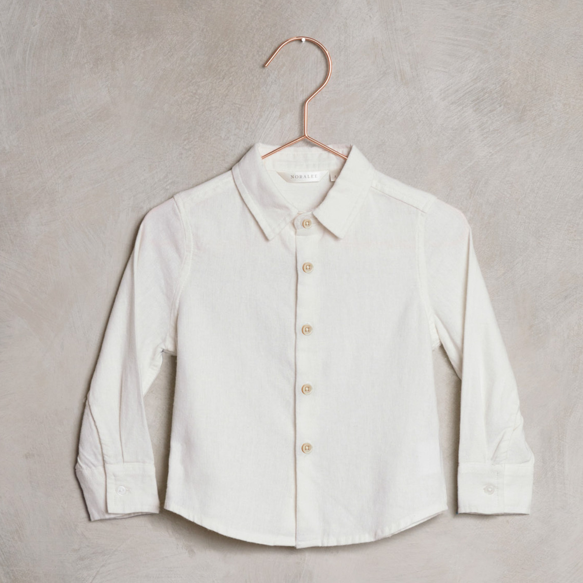 White collared shirt on a copper hanger against a textured gray background.