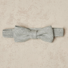 Silver bow tie on a light textured background, designed for formal wear or special occasions.