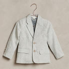 Light gray children's blazer on a hanger against a textured background.